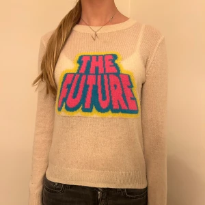 Beige tröja med 'The Future' tryck - Säljer en 100% Kashmir tröja  med ett coolt 'The Future' tryck i rosa, blått och gult. Tröjan är långärmad och perfekt för en avslappnad stil. Den är i bra skick och passar perfekt till jeans eller kjol. Perfekt för höst och vår! Köptes för 1900 säljer för 900kr