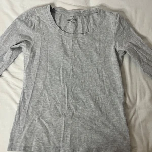 Grå långärmad tröja från Essentials - Säljer en enkel och bekväm grå långärmad tröja från Essentials. Perfekt för vardagsbruk med sin mjuka bomullskänsla. Passar bra till både jeans och kjol. Ett måste i basgarderoben!