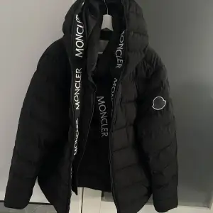 Säljer en snygg svart dunjacka från Moncler i mycket bra skick. Jackan har en pufferdesign med Moncler-logga på ärmen och dragkedja framtill. Perfekt för kalla vinterdagar. Storleken är i XL men passar även L.