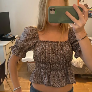 Blommig offshoulder topp - Säljer en söt blommig offshoulder topp med puffiga ärmar och volangdetaljer.  Älskar färgen och passformen🌸🌸