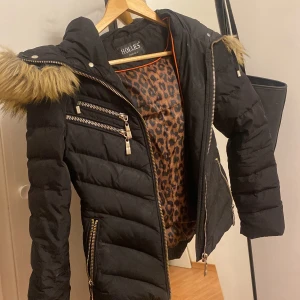 Svart pufferjacka från Hollies - Sjukt fin! Tyvärr inte min smak längre! Använd några gånger, det inte äkta päls, pälsen är avtagbar Passar storlek 34! Pris kan diskuteras