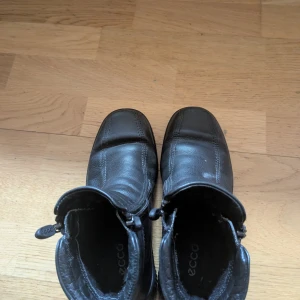 Ecco Svarta boots  - Säljer ett par svarta boots från Ecco i skinn. De har en praktisk dragkedja på sidan för enkel på- och avtagning. Perfekta för höst och vinter med sin robusta design och bekväma passform.