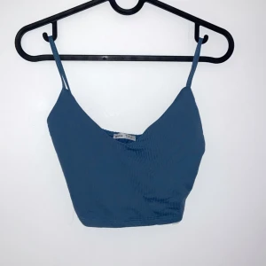 Blå ribbad linnetopp - Snygg blå ribbad linnetopp med smala axelband och v-ringning. Perfekt för sommardagar eller som ett lager under en tröja. Toppen är croppad och ger en trendig look. Passar bra till både jeans och kjol!