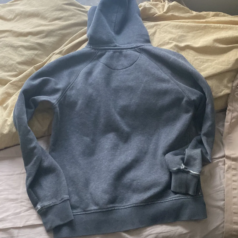 Säljer en snygg grå hoodie från GANT med broderad logga och ett coolt emblem på framsidan. Den har en klassisk känguruficka och är perfekt för både höst och vinter. Superbekväm och stilren, perfekt för vardagsbruk! Använd ganska länge . Hoodies.