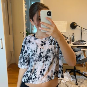 Svartvit mönstrad topp - Säljer en cool svartvit topp med abstrakt mönster. Den har korta ärmar och en avslappnad passform, perfekt för både vardag och fest. Materialet känns mjukt och bekvämt mot huden. Toppen är i mycket bra skick och redo för en ny garderob!