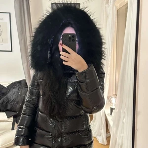 Svart glansig dunjacka med pälsdetaljer - Säljer en supervarm och snygg svart dunjacka med glansigt material och stor päls på huvan. Perfekt för kalla vinterdagar! Jackan har långa ärmar och en dragkedja framtill. Den är i mycket bra skick och passar perfekt för vinterns alla äventyr. Jackan är från femenina och nypris är 3799 och är använd 1-2 gånger. 