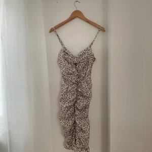 Blommig sommarklänning med volang - Söt blommig klänning perfekt för sommardagar! Den har smala axelband och en volangdetalj längst ner. Klänningen är i ett lätt och luftigt material, vilket gör den idealisk för varma dagar. Den har en tight passform som framhäver figuren.