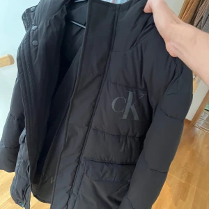 Svart dunjacka från Calvin Klein Jeans - Säljer en snygg svart dunjacka från Calvin Klein Jeans i storlek S. Jackan har CK-logga på bröstet och praktiska fickor. Perfekt för kyliga dagar. Passar både till vardags och lite finare tillfällen. Nypris 1700. Använd fåtal gånger dessutom.pris kan diskuteras vid snabb affär