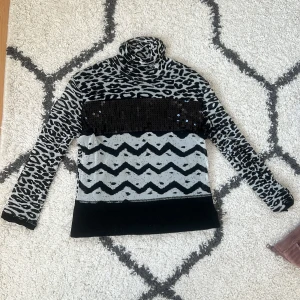 Mönstrad polotröja med paljetter - Säljer en unik polotröja med leopardmönster och zigzag-detaljer. Tröjan har en cool paljettpanel framtill som ger extra bling. Perfekt för höst och vinter! 🐆✨