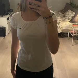 Lacost t-shirt - Super fin vit lacost t-shirt med snyggt urringning och lite piffigare ärmar. T-shirten är i strl Xs-S. Inga skador och knappast använd😊 köpte ny för 600kr säljer den för 250kr då den nästan aldrig blivit använd! (Pris kan diskuteras)