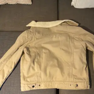 Säljer en snygg beige jacka med mjukt foder. Den har en klassisk design med knappar framtill och två bröstfickor. Perfekt för höst och vår när det är lite kyligt ute. Jackan har långa ärmar och en skön krage. Orginalpris 899kr!