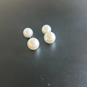 Dubbelpärlörhängen i vit - Säljer ett par eleganta dubbelpärlörhängen i vit. De har en stilren design med två pärlor i olika storlekar. Perfekta för både vardag och fest!