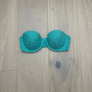 Turkos axelbandslös bh från Victoria's Secret - Säljer en superfin turkos axelbandslös push up bh från Victoria's Secret. Den har en snygg spetsdetalj och passar perfekt som både bh och bikinitopp då den är gjord 100% av nylon.