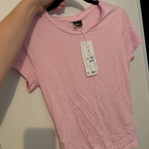 Rosa T shirt från Gina - Helt ny T-shirt från Gina. Lite skrynklig på bilden pga legat vikt i gaderoben.  Helt ny, med prislapp kvar!  