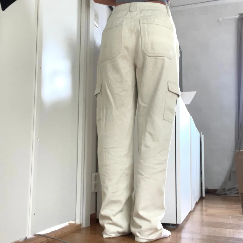 Säljer ett par snygga beige cargobyxor med hög midja. De har flera praktiska fickor på sidorna och en loose passform som ger en avslappnad stil. Perfekta för både vardag och äventyr!. Farkut & Housut.
