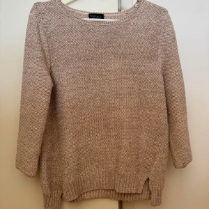 Beige stickad tröja från Topshop - Säljer en supermysig rosa glittrig stickad tröja från Topshop. Den har en avslappnad passform och är perfekt för höst och vinter. Tröjan har 3/4 långa ärmar och en rund halsringning. Perfekt för att hålla sig varm och stilren under kyliga dagar!