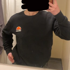 Svart sweatshirt från Ellesse - Svart sweatshirt från Ellesse i storlek L men som sitter mer som en M. Tröjan har en klassisk rund halsringning och det ikoniska Ellesse-logotypen på bröstet. Loggan kan vara lite skrapad efter tvätten men inget som syns mycket eller som man tänker på, i övrigt bra skick!