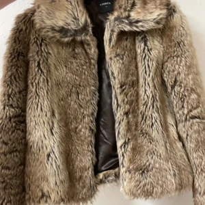 Beige pälsjacka från Lindex - Säljer en supermjuk och fluffig beige pälsjacka från Lindex. Den är perfekt för att hålla sig varm och stilren under kyliga dagar. Jackan har en klassisk krage och är helfodrad för extra komfort. Passar perfekt till både vardag och fest!