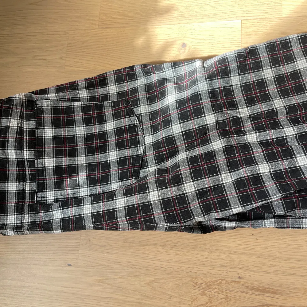 Säljer ett par snygga rutiga byxor från Bonita. De är svart- och vitrutiga med inslag av rött, vilket ger dem en cool look. Byxorna har en rak passform och är perfekta för en avslappnad stil. De har en praktiska fickor och är gjorda i ett bekvämt material. ett hål är lagat i grenen- se bild. Farkut & Housut.