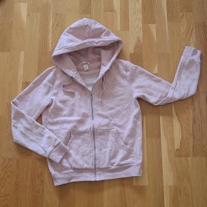 Ljusrosa hoodie med dragkedja - Säljer en supermysig ljusrosa hoodie i storlek XS. Den har en dragkedja framtill och en stor, bekväm huva med snören. Perfekt för kyliga dagar eller mysiga hemmakvällar. Den har också praktiska fickor framtill. Köparen står för frakten 