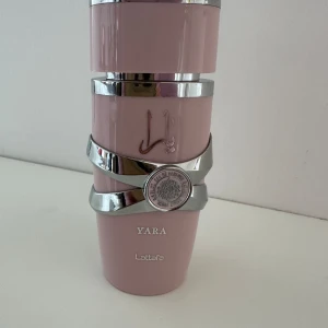 Yara EDP från Lattafa - Yara EDP från Lattafa är en förtrollande och sofistikerad doft som kombinerar blommor och fruktnoter för en unik och feminin aura. Flaskan är elegant i ljusrosa med silverdetaljer och rymmer 100 ml, perfekt för både vardag och fest. En lyxig touch till din personliga stil. Enbart testad med 3 spray