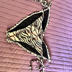 Zebramönstrad bikini med knytband - Säljer en superfin zebramönstrad bikini från Nelly . Den har knytband i sidorna och är perfekt för sommaren. Bikinin är i nyskick och har en snygg mörkbrun och ljusbrun design. Perfekt för både stranden och poolen! 🏖️