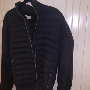 Moncler Cardigan - Säljer en asfet Moncler Cardigan. Skick: 8/10 . Den har fortfarande mycket liv kvar i sig!  Hör av er för bild på defekterna. Storlek M men passar även S! Färgen är marinblå och den har black label🤩 Nypris: ca 10000kr, vårt pris: 2500 kr!