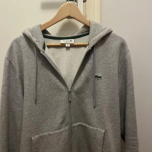 Lacoste hoodie  - Hej säljer denna Lacoste zip hoodie i storlek L, hoodien är i perfekt skick använd fåtal gånger, skriv gärna om ni har några frågor