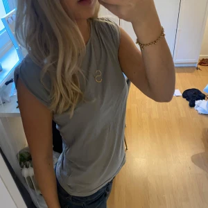 Grå kortärmad tröja - Säljer då jag har för många basic tröjor. Har snygga rynkdetaljer vid axlarna och dragkedja på ryggen💕