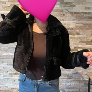 Svart fluffig jacka - En svart, kort, fluffig jacka från NA-KD i storlek 34. Jackan är i bra skick, nästan som ny då den används 4 gånger ungefär. Jätte mysig till hösten då den håller värmen bra. 