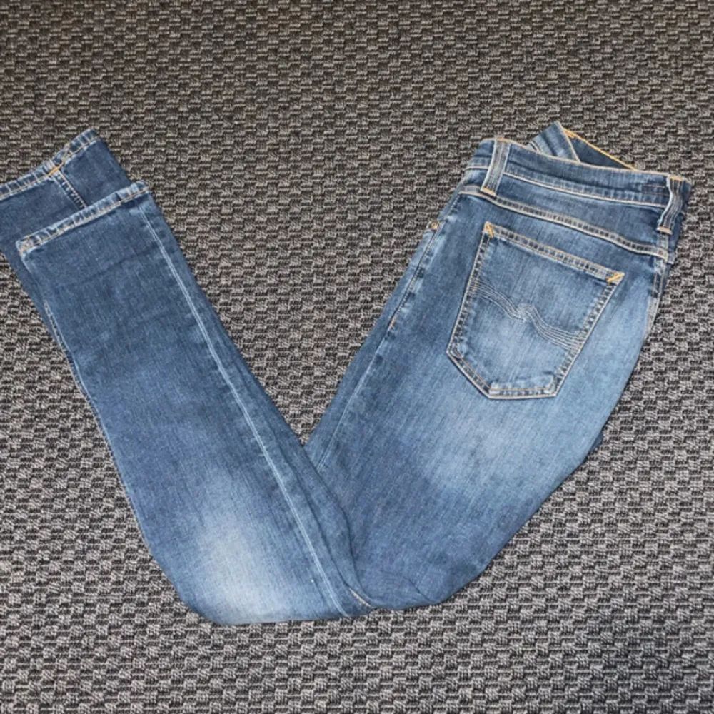 Säljer ett par snygga blå jeans i slim modell. De är i en ljusblå färg och har en klassisk femficksdesign. Materialet är 93% bomull, 6% polyester och 1% lycra, vilket gör dem både bekväma och stretchiga. Perfekta för vardagsbruk!. Jeans & Byxor.