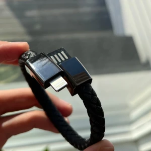 Svart flätat laddar armband - Säljer ett svart flätat armband som också fungerar som en USB-kabel till iPhone. Armbandet har en stilren design med en metallisk låsning som döljer USB-kontakten. Jättebra skick🔥🔥🔥vid frågor kontakta 