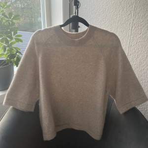 Beige stickad t-shirt i alpacka från & Other Stories i storlek S. Den är i fint skick och har inga defekter. Nypris är 790 kr.