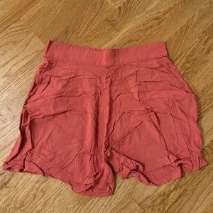 Rosa shorts - Säljer ett par snygga rosa shorts som är perfekta för sommaren. De har en loose passform och är gjorda i ett mjukt material som känns skönt mot huden. Perfekta för en avslappnad dag på stranden eller en promenad i parken. Korall färgad 