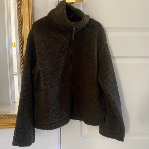 NY mörk khakigrön pilejacka från HM - Ny och oanvänd mörkgrön teddyjacka  Storlek: L  Passformen är i en normal avslappnad form. Ta en storlek större än din vanliga storlek om du vill ha plats för en tjocktröja under. har du normalt S eller M i vanliga fall så blir denna lagom oversize. 