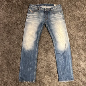 Blå jeans från Diesel - Snygga blå Diesel Larkee jeans med en straight passform. De har en klassisk femficksdesign och en fet tvättad look. Perfekta för en avslappnad stil.