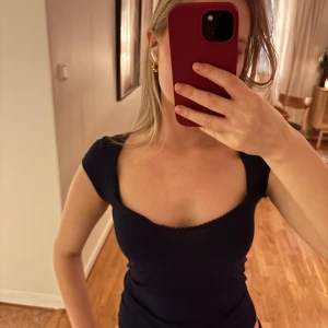 Mörkblå tight topp - Snygg mörkblå topp med tight passform och korta ärmar. Perfekt för en stilren look. Från Nelly, slutsåld på hemsidan.