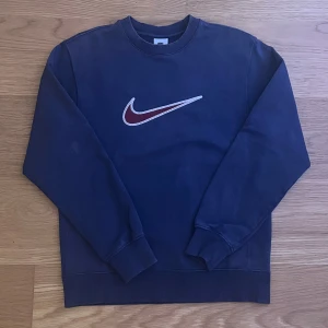 Vintage blå sweatshirt från Nike - Säljer nu denna Blåa sweatshirt från Nike eftersom jag har växt ur den. Det är en gammal vintage modell som kan vara hyfsat svårt att hitta. Tröjan är i bra skick för åldren. Den har en fläck på undersida vänster ärm (se bild 1). Den är även lite skadad längst ned på ärmarna              (se bild 3).
