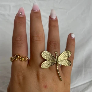 Guldfärgad ring med trollslända - Har i silver också! Pris kan diskuteras. Frakt ingår i priset åvan. Detta är en unik guldfärgad ring med en stor trollslända som dekoration. Perfekt för att ge en extra touch till din outfit. Ringen har en justerbar storlek för att passa de flesta. Alldrig kommit till användning så är i nyskick. Köpt för 250kr och säljer därför för 140kr inkl frakt.