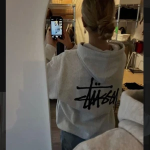 Grå hoodie från Stüssy - Säljer en grå hoodie från Stüssy med deras ikoniska logga i svart på ryggen och bröstet. Hoodien har en klassisk passformen. Säljer den relativt billigt eftersom att den bara tar upp plats i garderoben💗 