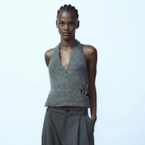 Grå ärmlös topp - Snygg grå ärmlös topp med djup v-ringning och en stilren design. Perfekt för en modern och minimalistisk look.