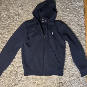 Ralph lauren zip hoodie - Snygg mörkblå  hoodie från Ralph Lauren.  Skicket är precis som nytt, bara använd fåtal gånger. Skriv vid frågor och funderingar!
