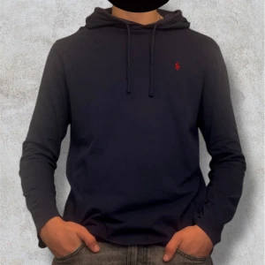 Mörkblå hoodie från Ralph Lauren - Säljer en stilren mörkblå hoodie från Ralph Lauren med det klassiska röda broderade logotypen på bröstet. Tröjan har långa ärmar och en justerbar huva med snören. Perfekt för en avslappnad stil. Storlek M. Mycket fint Skick. Kan gå ner lite i pris vid en snabb affär! Hör av dig vid frågor eller funderingar! Postar alltid inom 24h!