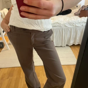 Lågmidjade kostymbyxor  - Dem perfekta lågmidjade kostymbyxorna!! Super fin brun färg och snygga detaljer på fickorna bak.