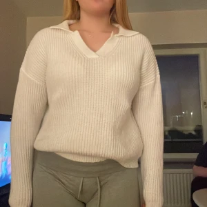 Vit stickad tröja - Säljer en stilren vit stickad tröja med krage och v-ringning. Tröjan har långa ärmar och en bekväm passform, perfekt för kyligare dagar.