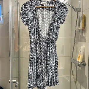 Mönstrad klänning från & Other Stories - Söt klänning med ett hjärtmönster i svart och vitt från & Other Stories. Den har en v-ringad design och korta ärmar, perfekt för en somrig look. Klänningen är i en lätt och luftig stil.