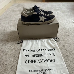 Mörkblåa sneakers från Golden Goose - Snygga svarta sneakers från Golden Goose med vit stjärndetalj på sidan. Skorna har en klassisk snörning och en vintage-look med slitna detaljer. Perfekta för en avslappnad stil.