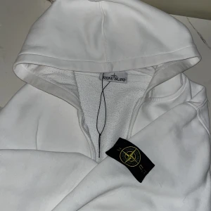 Vit hoodie från Stone Island - Säljer en stilren vit hoodie från Stone Island med dragkedja och den ikoniska loggan på ärmen. Perfekt för en avslappnad look helt äkta men ingen kvitto