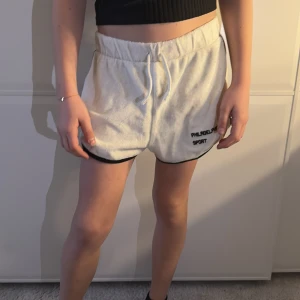 Vita sportshorts från Philadelphia Sport - Snygga vita sportshorts  med svart kant och elastisk midja. Perfekta för en aktiv dag eller bara för att chilla. De har en avslappnad passform och är gjorda i ett mjukt material.