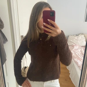 Brun stickad tröja från Pieces - Säljer en mysig brun stickad tröja från Pieces. Tröjan har en enkel design med långa ärmar och rund halsringning. Perfekt för kyligare dagar! Köpt för ungefär 2 år sedan men inte använt mycket. 